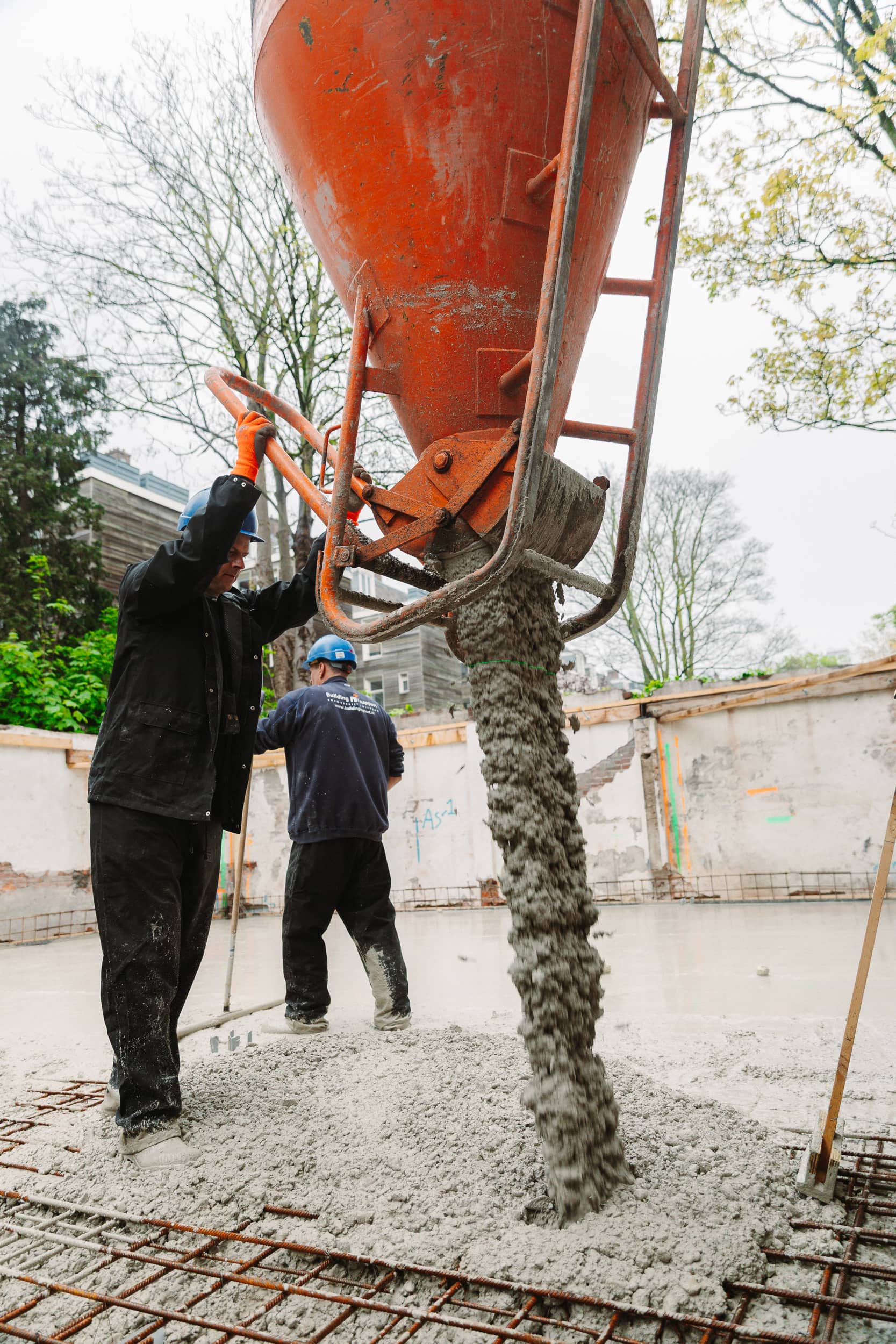 Storten van een betonvloer op wapeningsnetten tijdens funderingswerk - Bouwcon